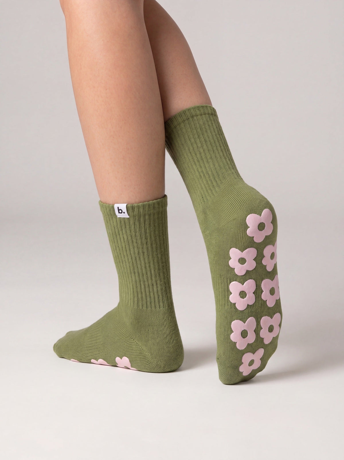 Olive green pilates grip socks with pink silicone flower grips on the sole