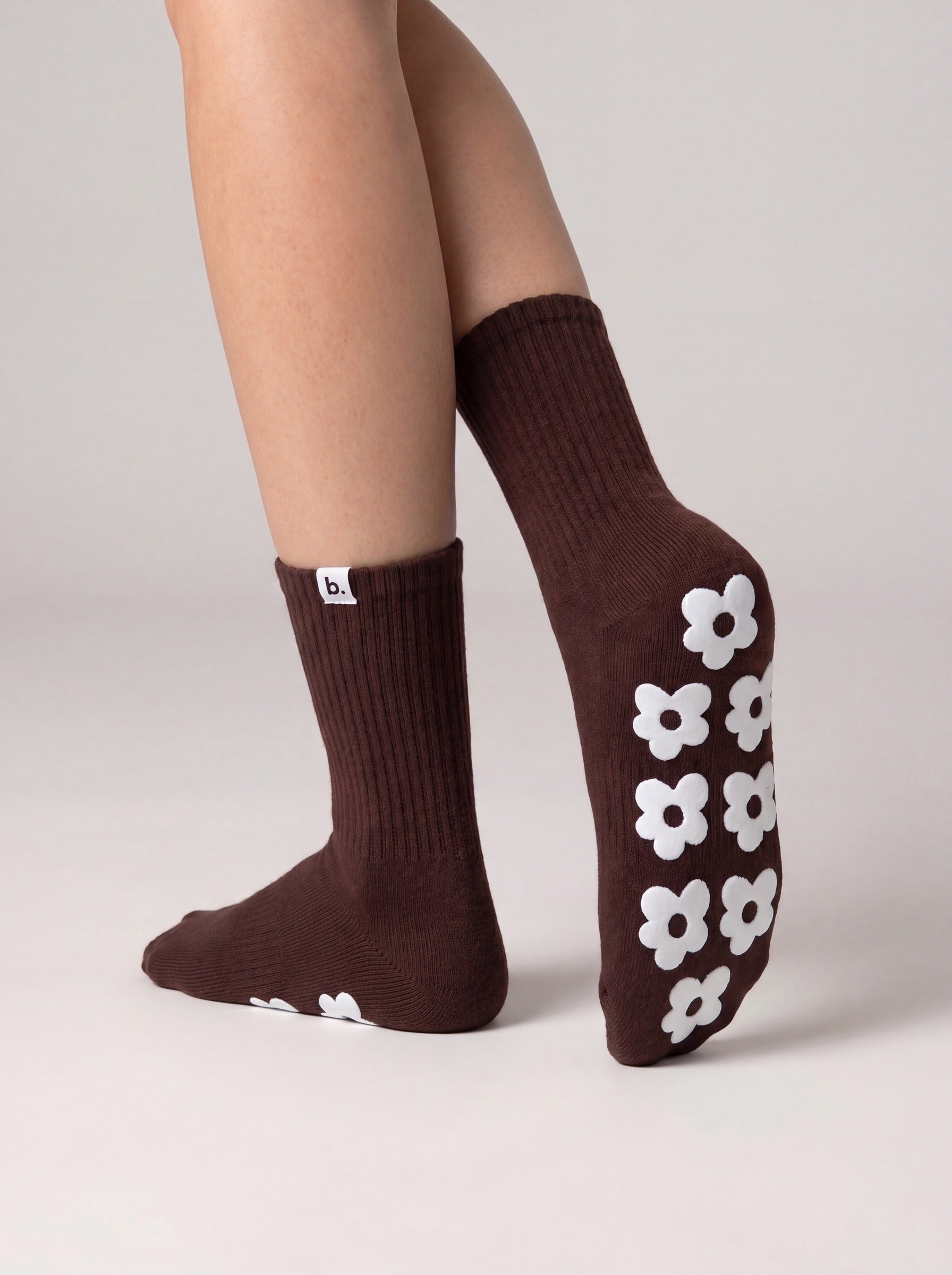 Pilates grip socks in chocolate brown with off-white silicone flower grips on the sole, top view