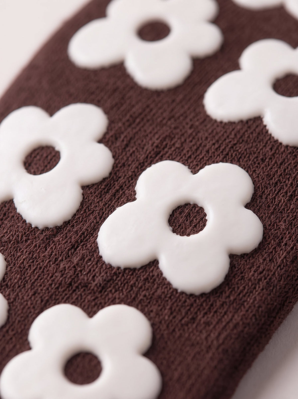 Close-up of chocolate brown balanced. grip socks with white silicone flower grips