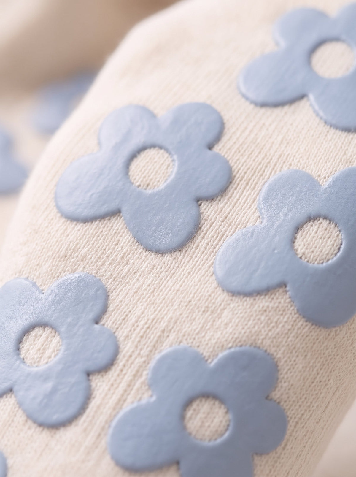 Close-up of cream balanced. grip socks with sky blue silicone flower grips
