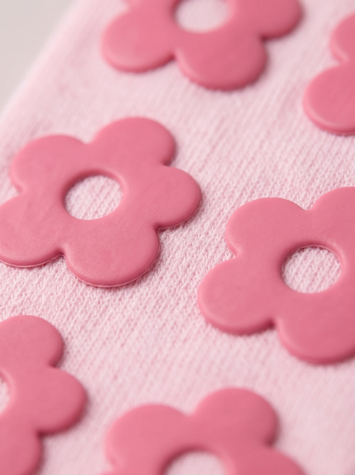 Close-up of soft pink balanced. grip socks with rose silicone flower grips